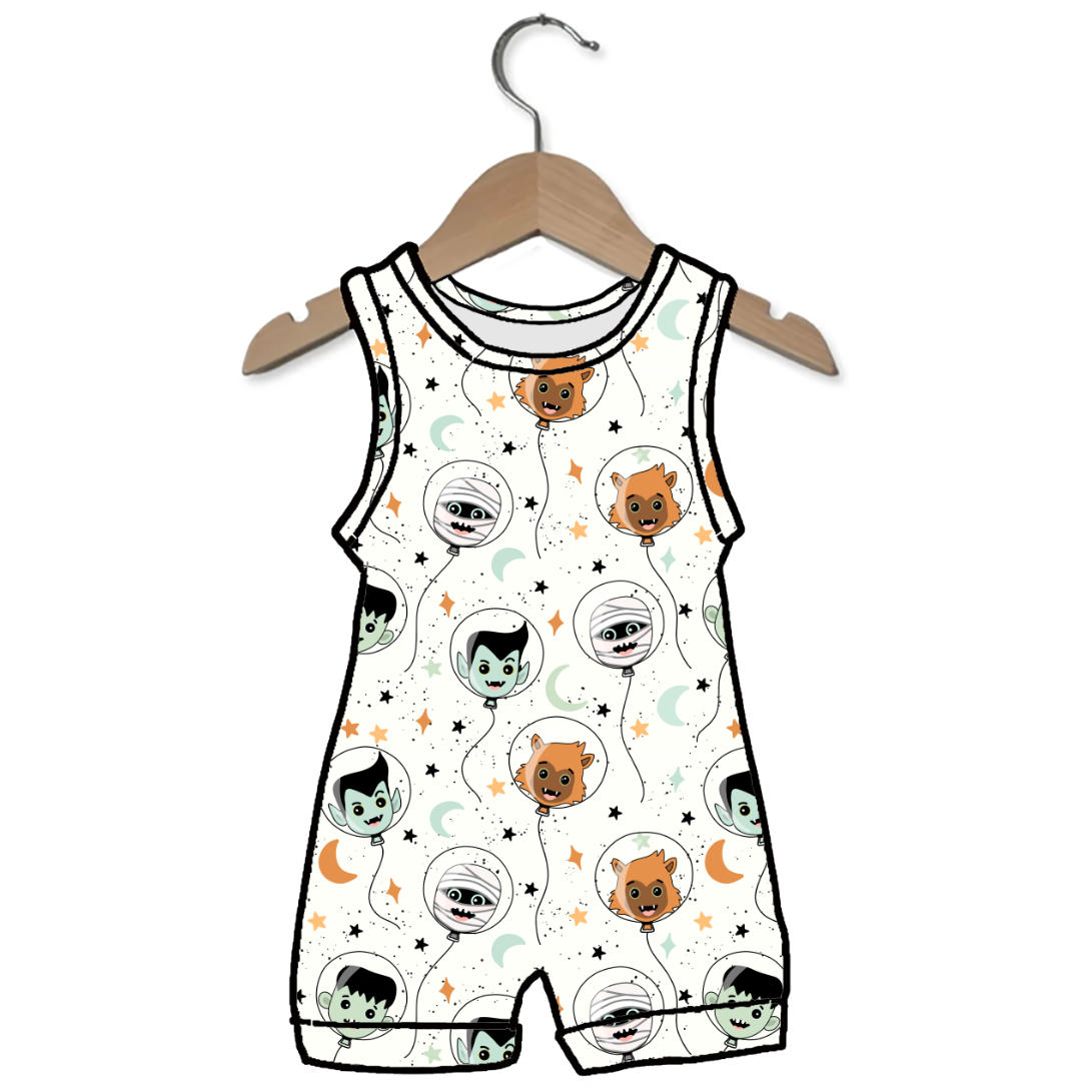A sleeveless baby romper with a white background and a cartoon space-themed print featuring monsters in space, hanging on a wooden hanger against a white background.