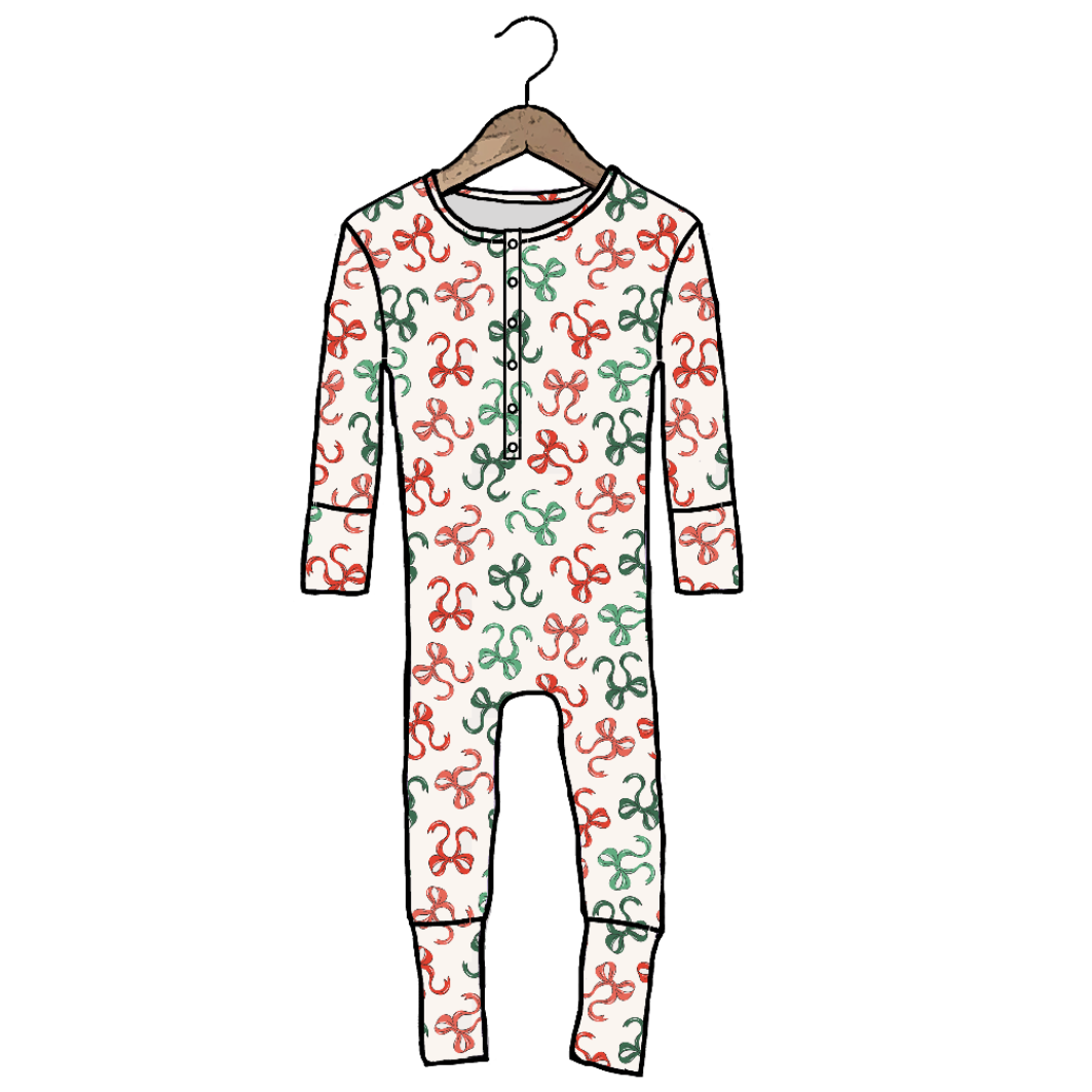 A long-sleeve baby jumpsuit with an all-over red and green abstract squiggle pattern on a white background, hanging from a wooden hanger against a plain white background.