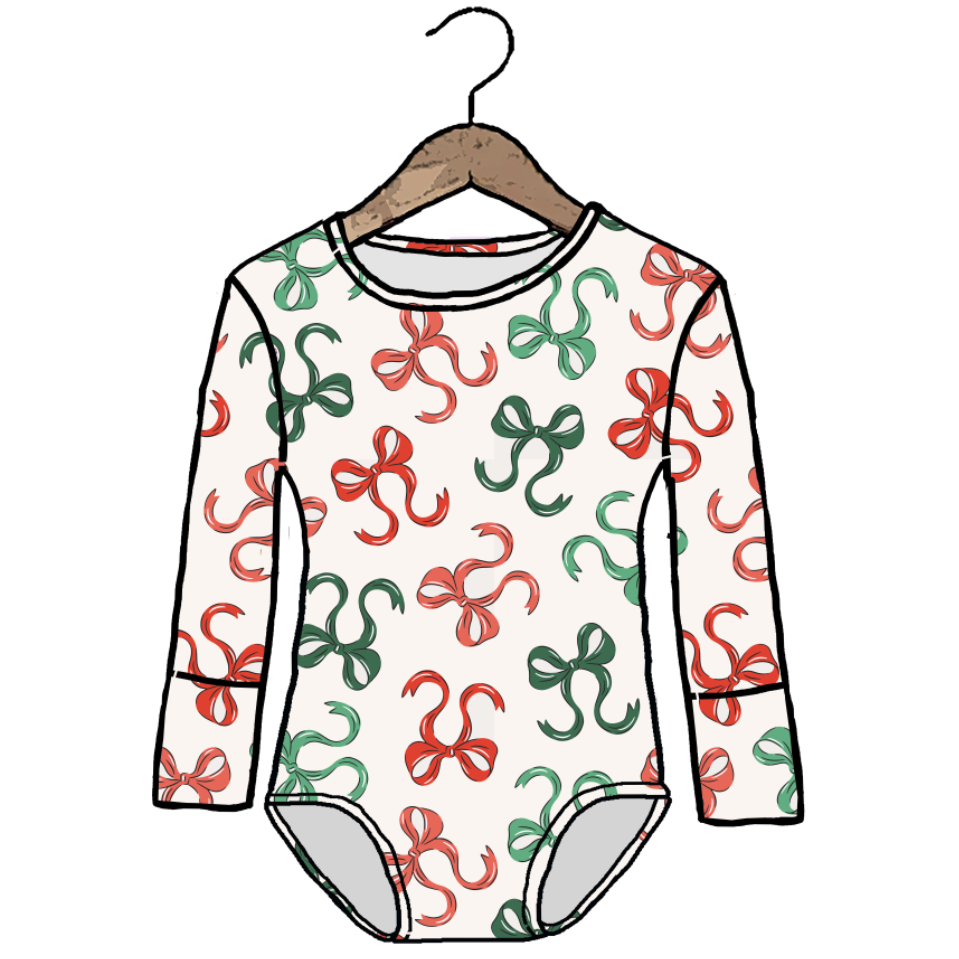 A long-sleeve baby bodysuit with an all-over repeating bow pattern in red and green on an off-white background, shown hanging on a wooden hanger against a white background.