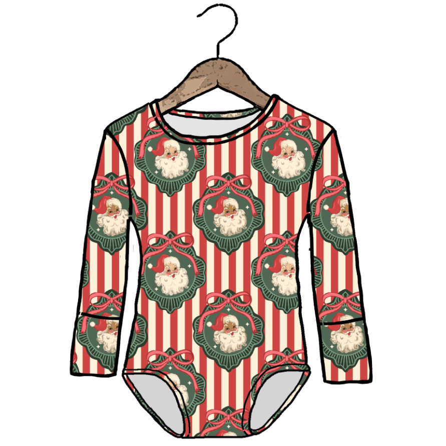 A long-sleeve baby bodysuit with a festive Christmas print, featuring red and white vertical stripes, green wreaths with Santa silhouettes, and red bows, shown on a wooden hanger against a white background.