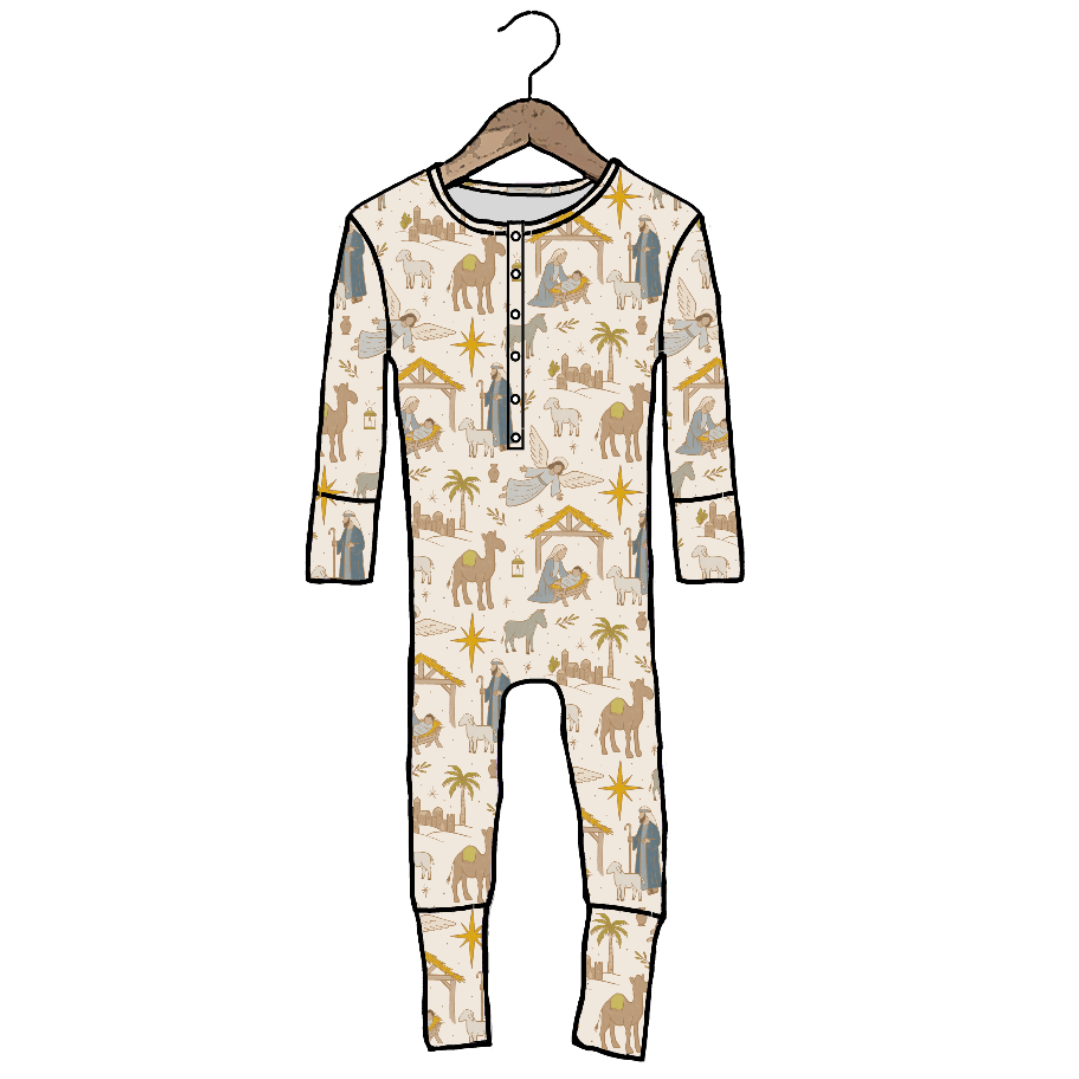 A long-sleeve baby jumpsuit with a camel and desert-themed print, hanging on a wooden hanger against a plain white background.