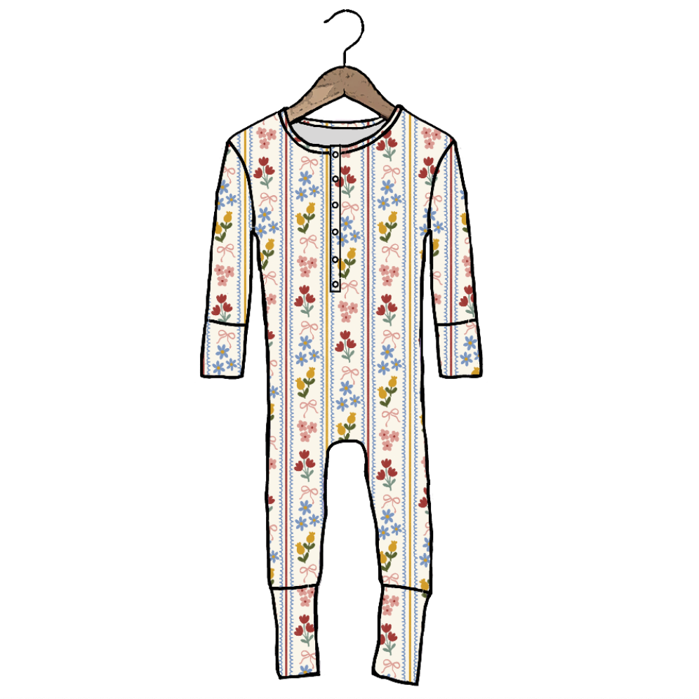 A long-sleeve baby jumpsuit or footed romper shown on a hanger against a plain white background. The garment has a white base with vertical multicolor floral and star-like patterns in red, blue, yellow, and green, plus a short front button placket.