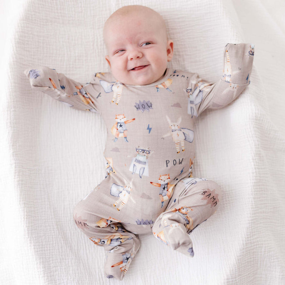 Baby lying on a white blanket wearing a patterned onesie.