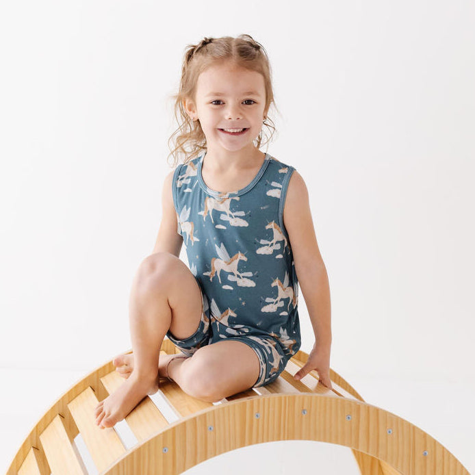 Child sitting on a wooden climbing toy against a white background