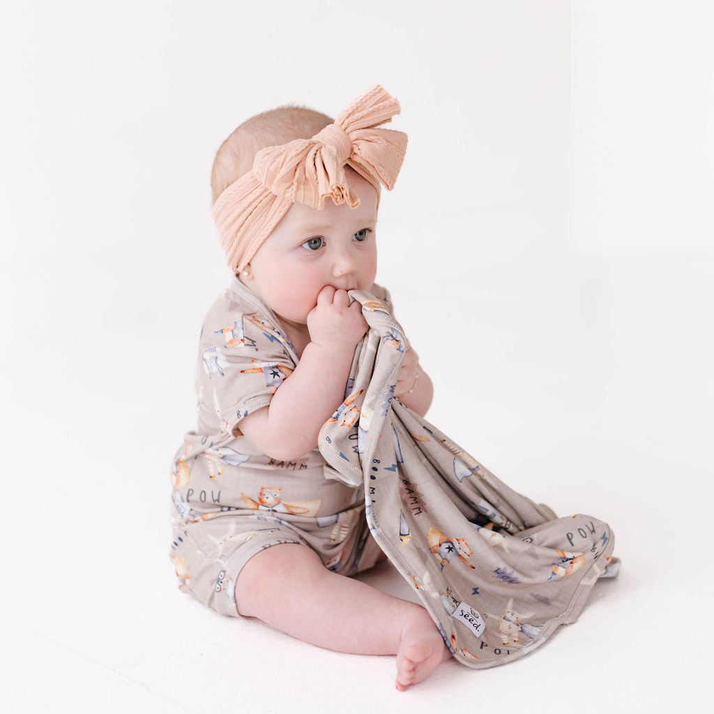 Baby wrapped in a floral blanket with a headband on a white background