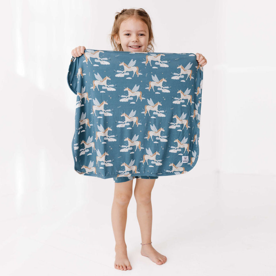 Child holding a blue blanket with fairy pattern on a white background