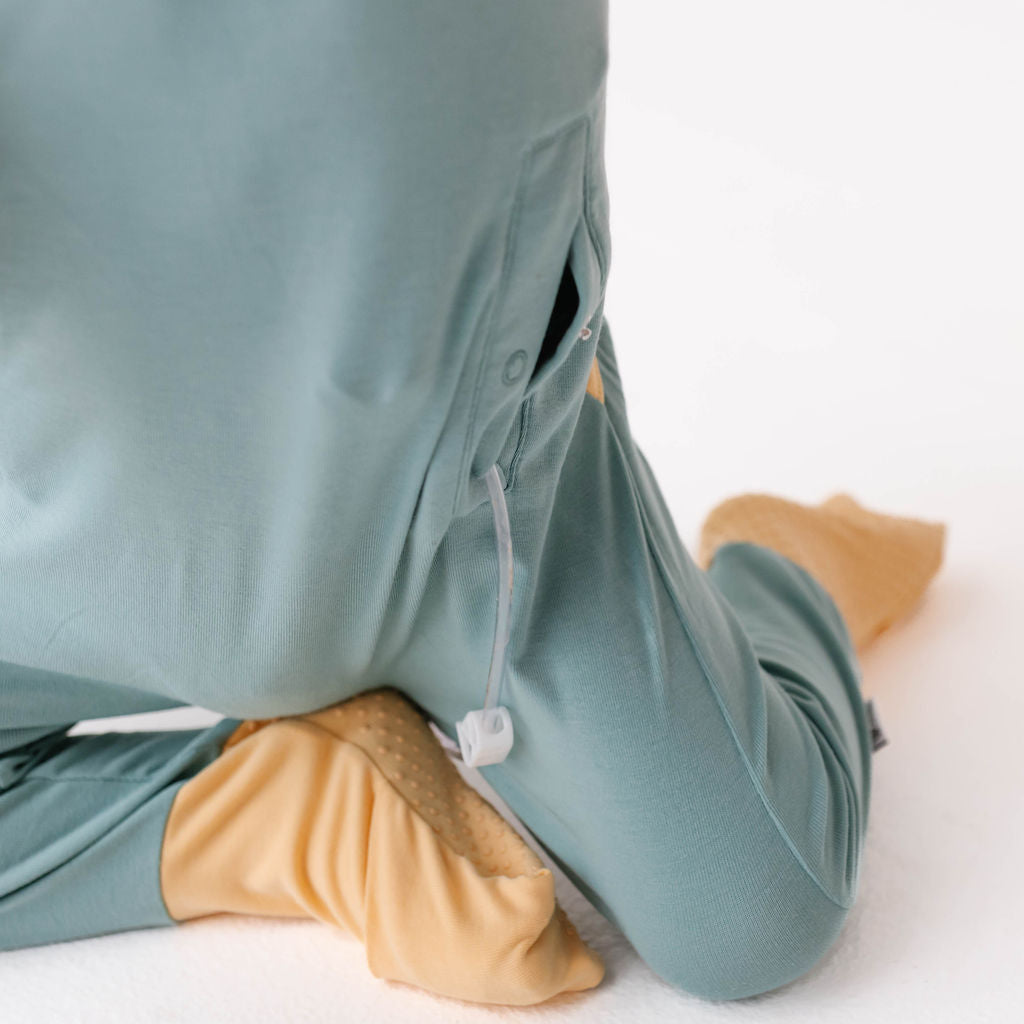 Person wearing teal pants with beige foot covers on a white background