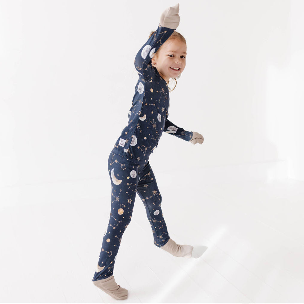Child wearing a navy blue onesie with space-themed print on a white background