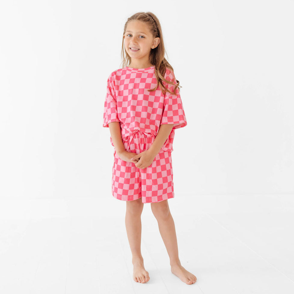 Young girl wearing a pink checkered dress on a white background