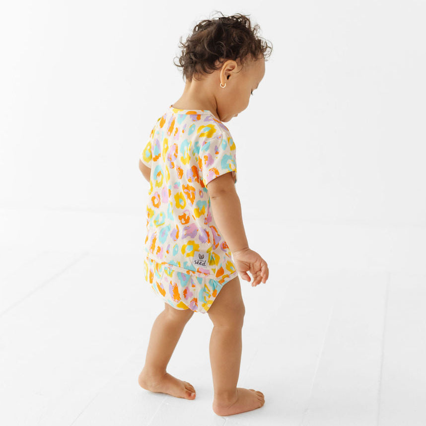 Child wearing a colorful floral onesie on a white background
