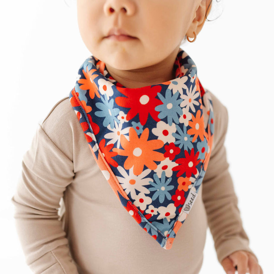 Child wearing a colorful floral bib on a white background