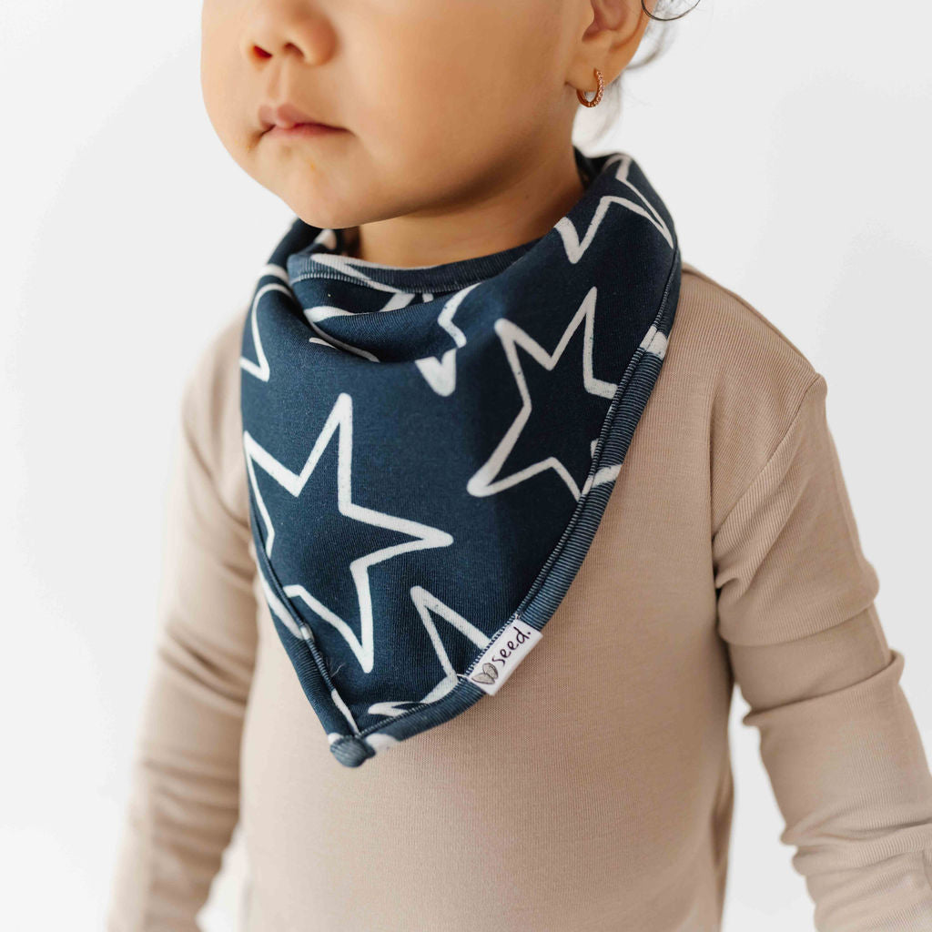 Child wearing a navy blue bandana with white star patterns on a plain background