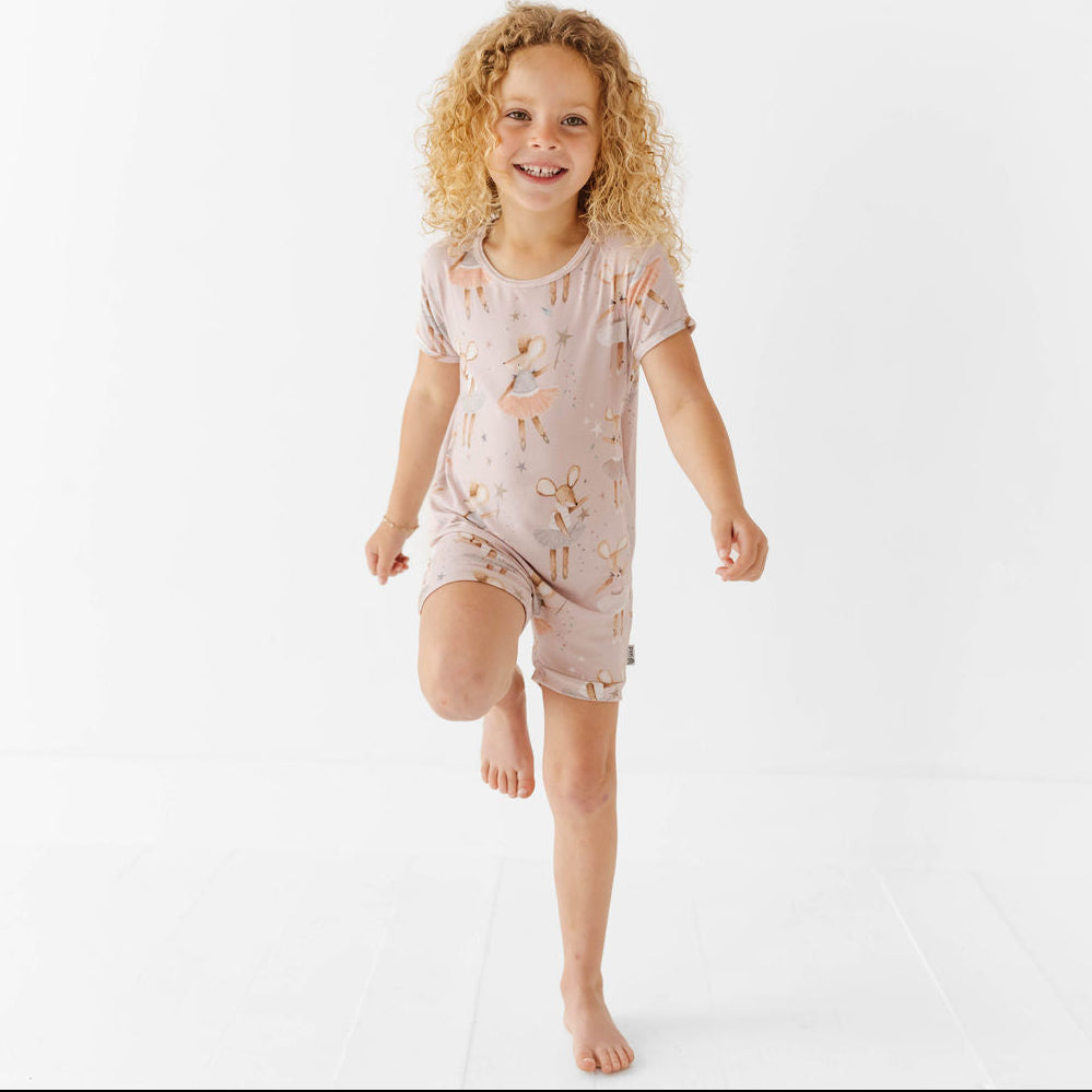Child wearing a pink pajama set with animal prints on a white background