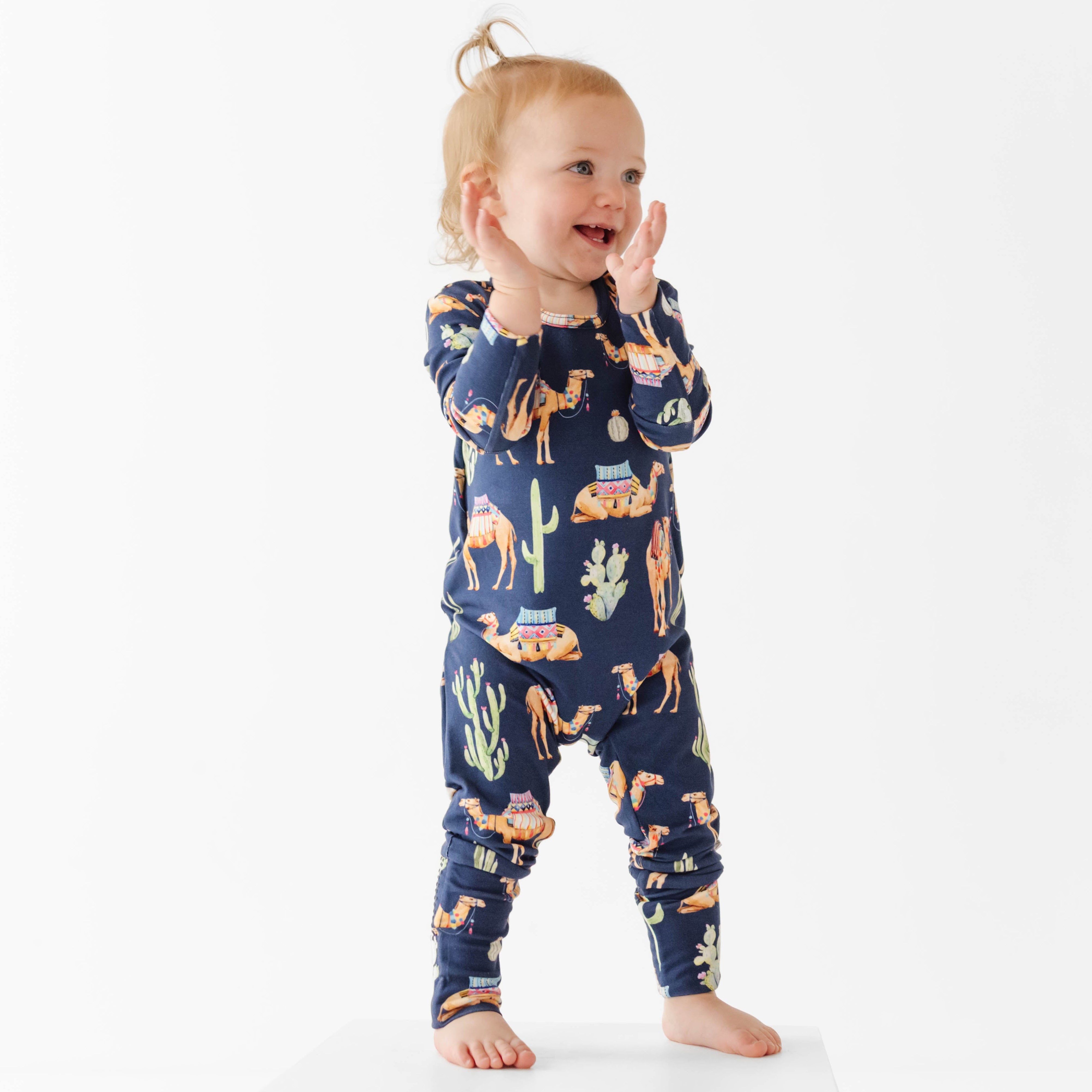 Child wearing a navy blue pajama set with camel pattern on a white background
