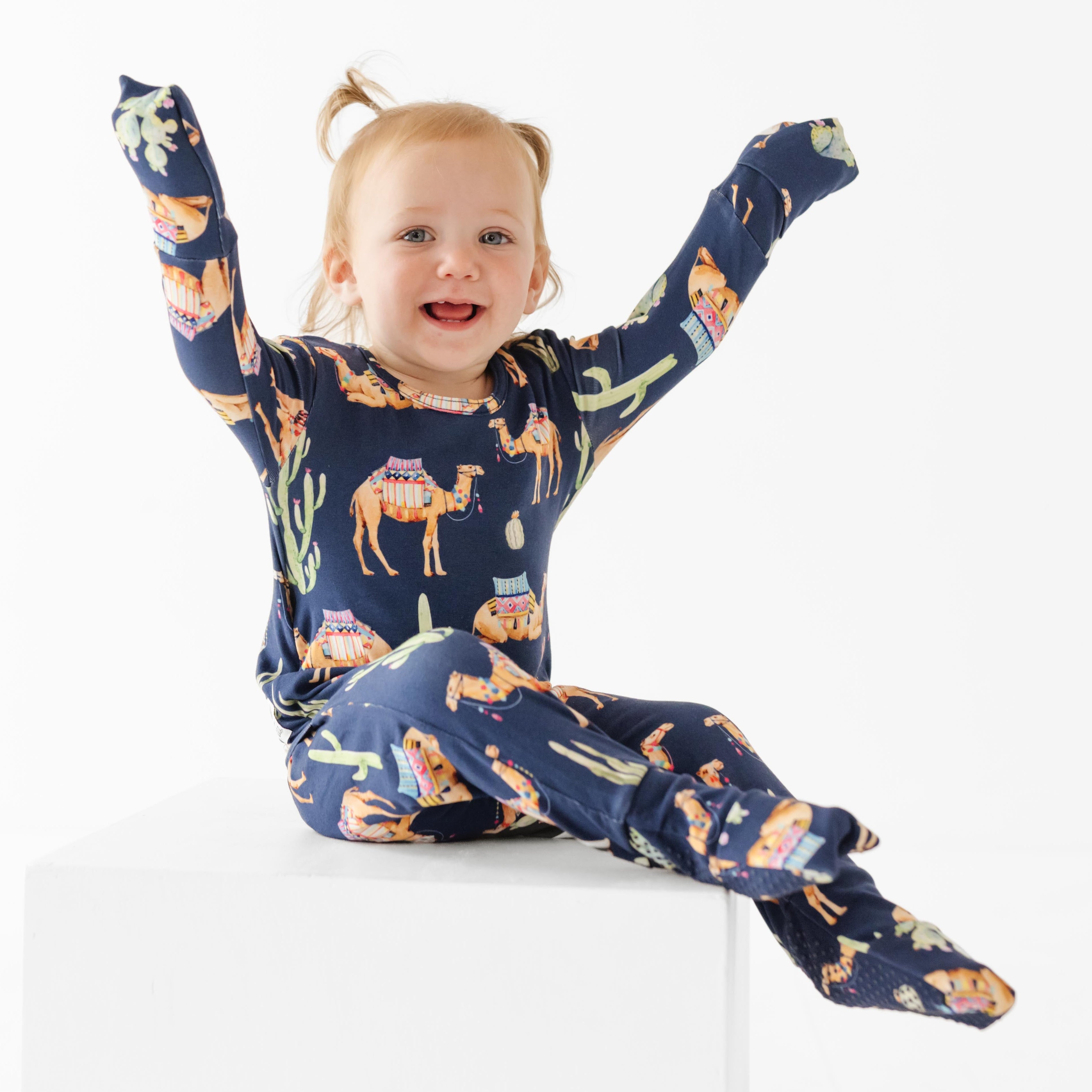 Child wearing a navy blue pajama set with animal prints on a white background
