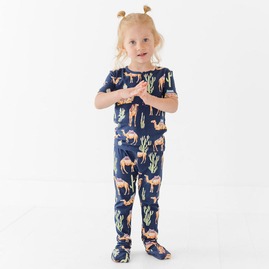 Child wearing a navy blue pajama set with animal prints on a white background