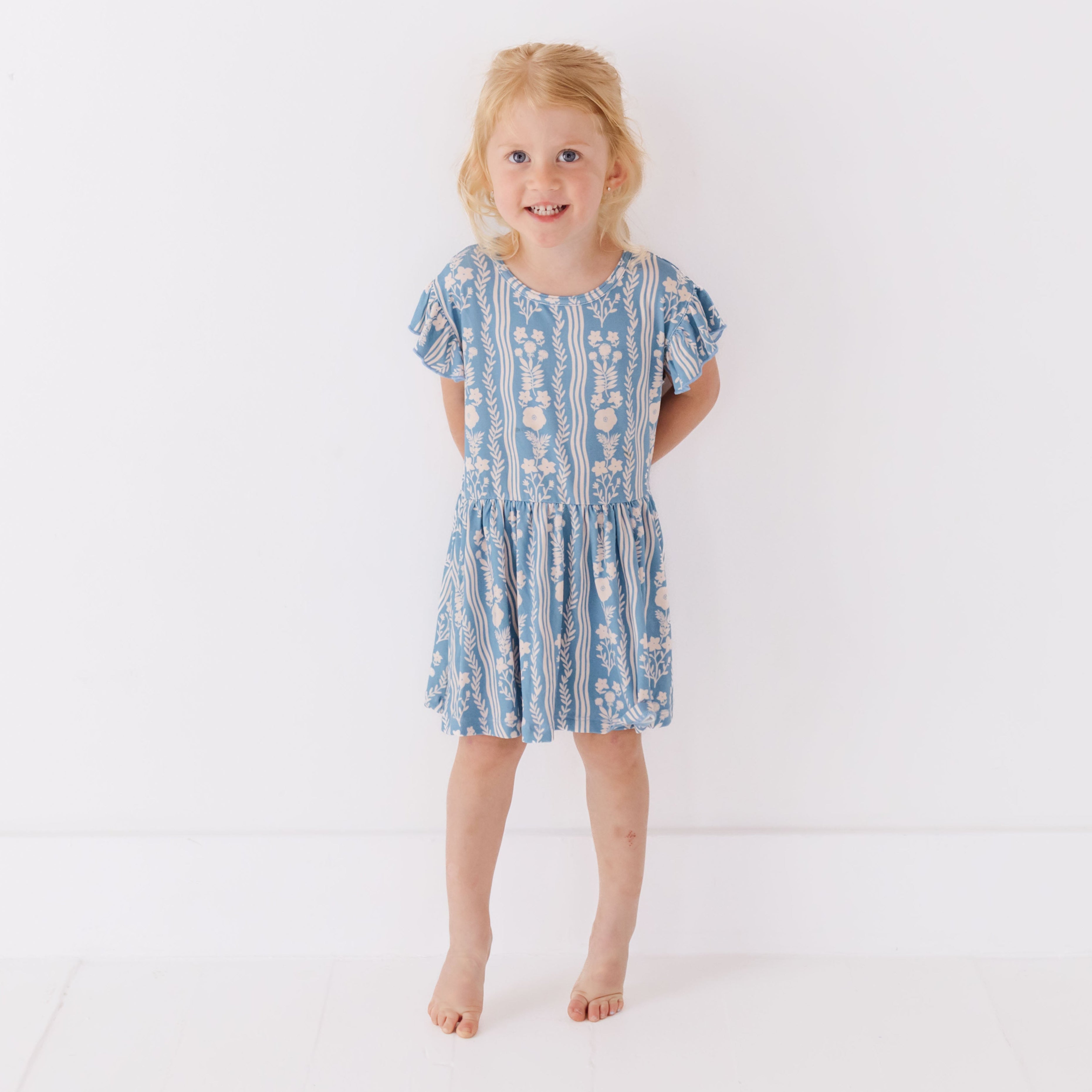 Young girl wearing a blue patterned dress on a white background
