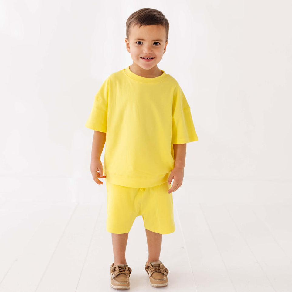 Child wearing a yellow outfit on a white background