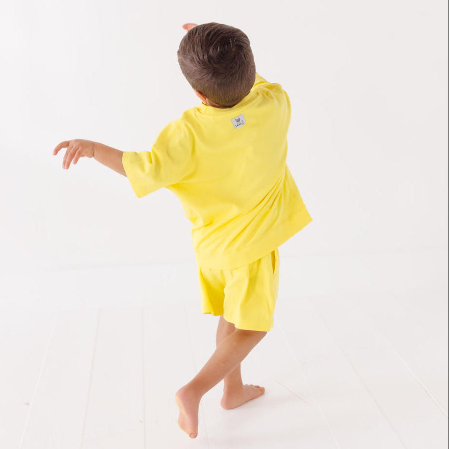 Child wearing a yellow outfit on a white background