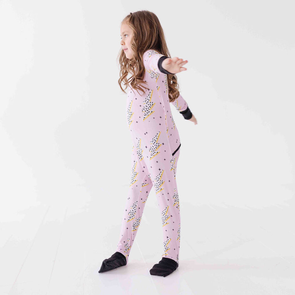 Child wearing a pink onesie with black and yellow patterns on a white background