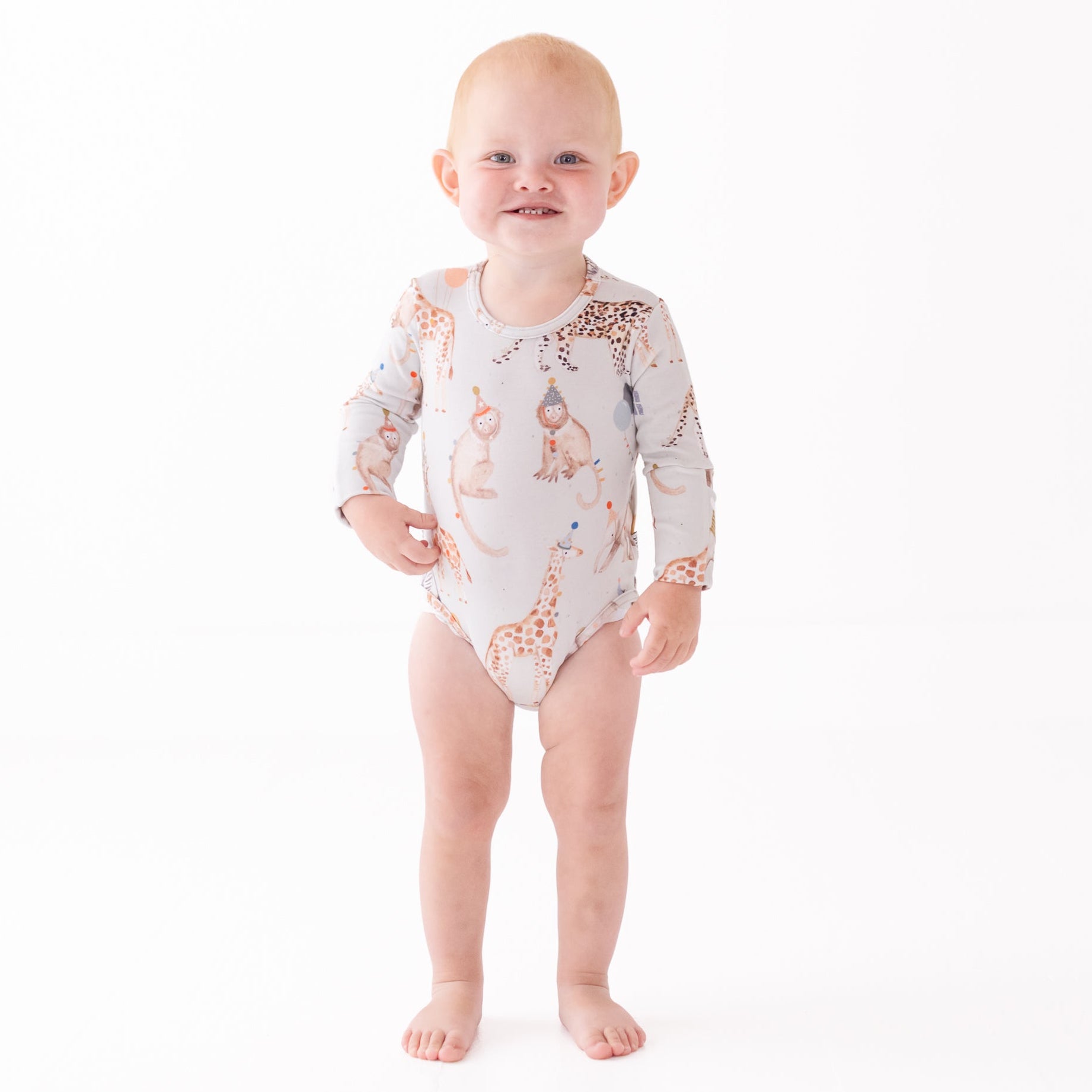 Baby wearing a long-sleeve onesie with animal pattern on a white background
